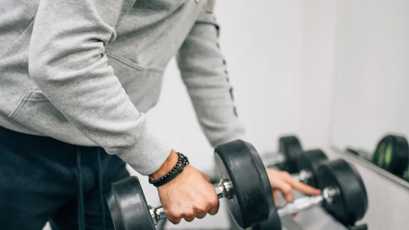 Man lifting a dumbbell from a rack at the gym