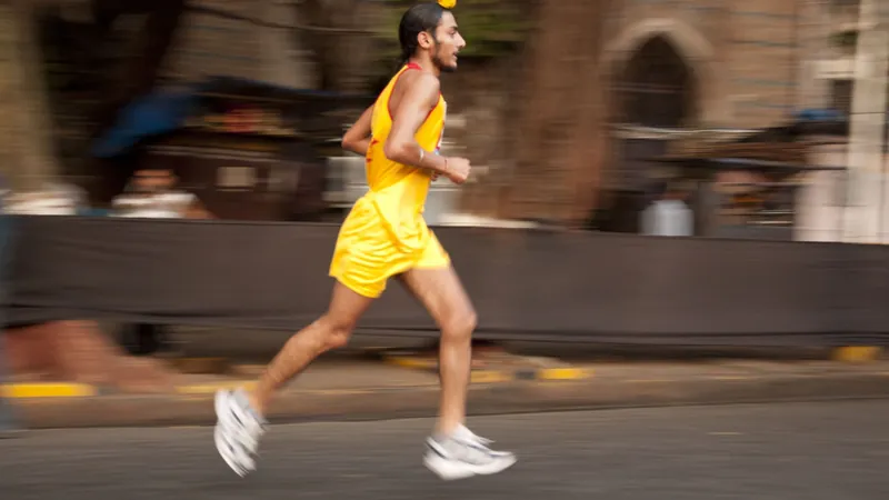 Runner in a yellow vest mid-stride at the Mumbai Marathon