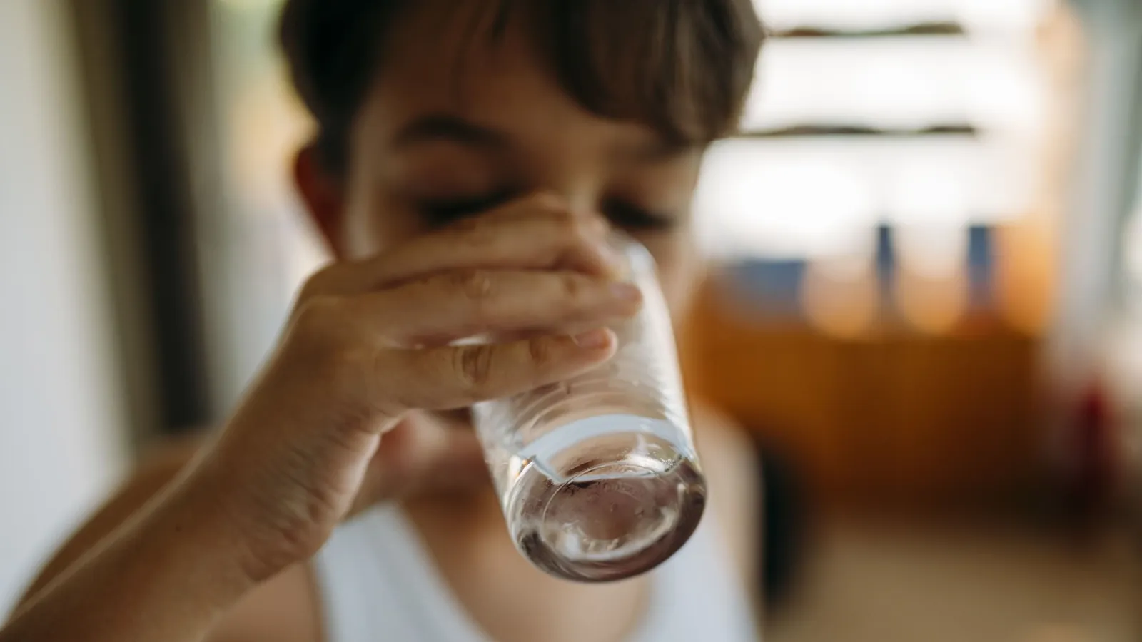 Boy drinking a glass of water at home