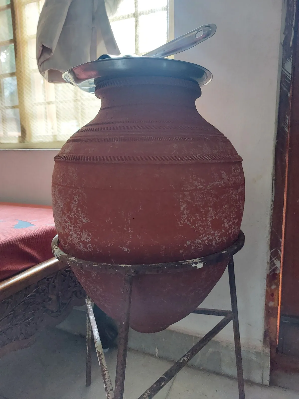 Traditional red clay mitti ka matka water pot on a metal stand